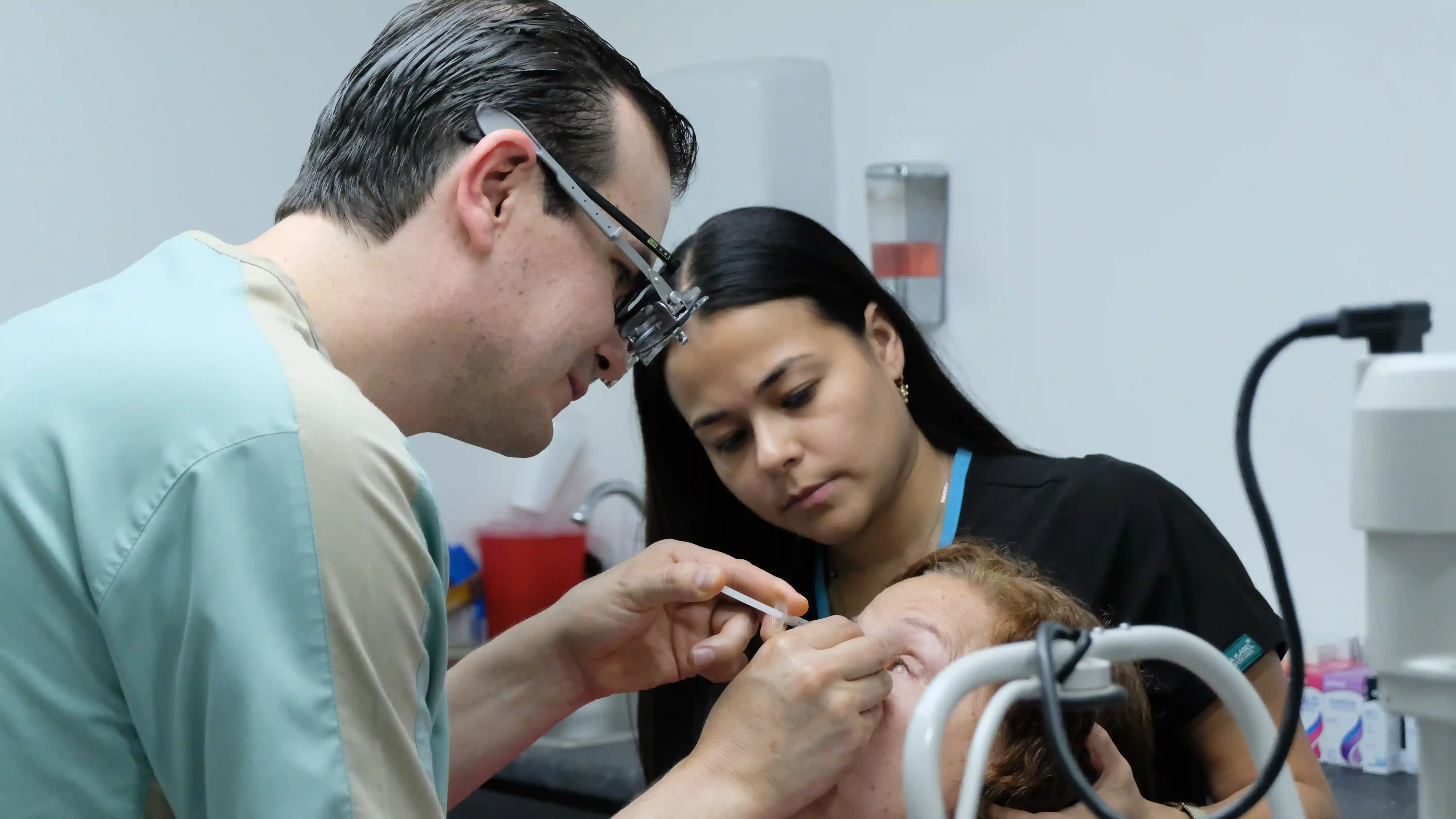 Oftalmólogo aplicando un tratamiento láser en el ojo de un paciente.